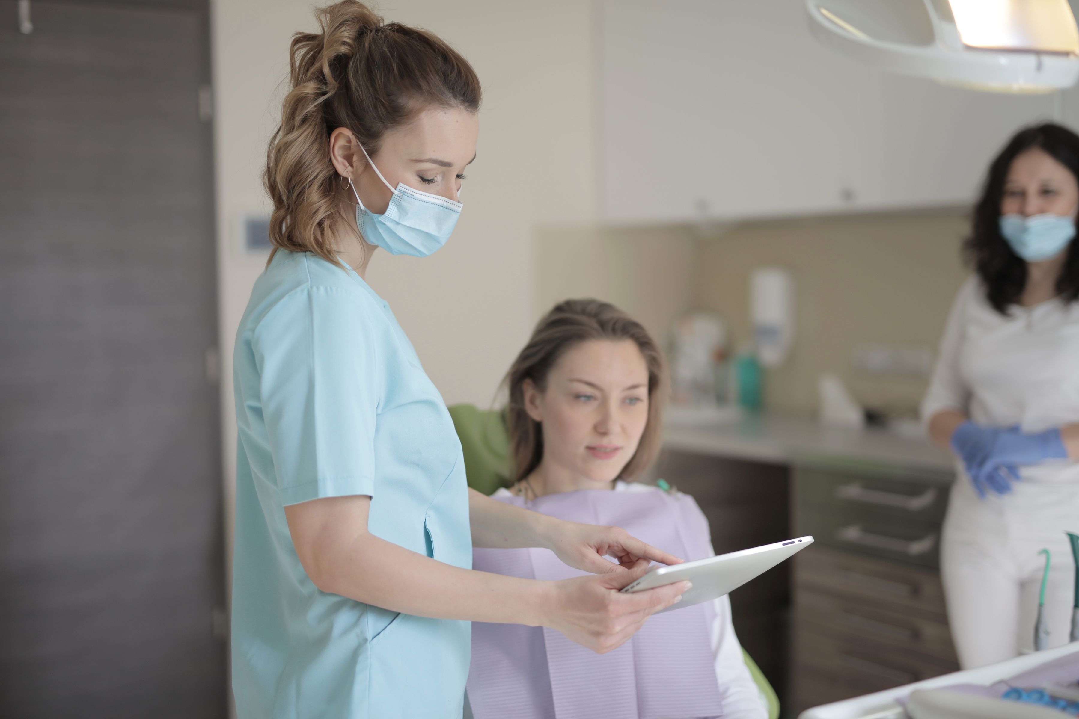 Dental clinic staff reviewing patient information on a tablet, representing recall and reactivation tracking