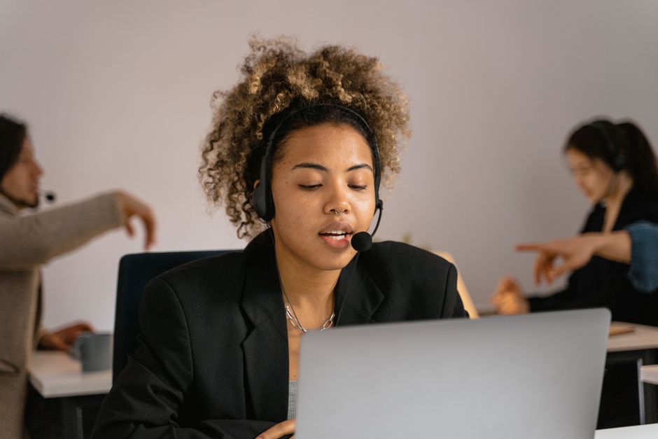 A call center agent wearing a headset while working at a laptop, representing a live-operator answering service