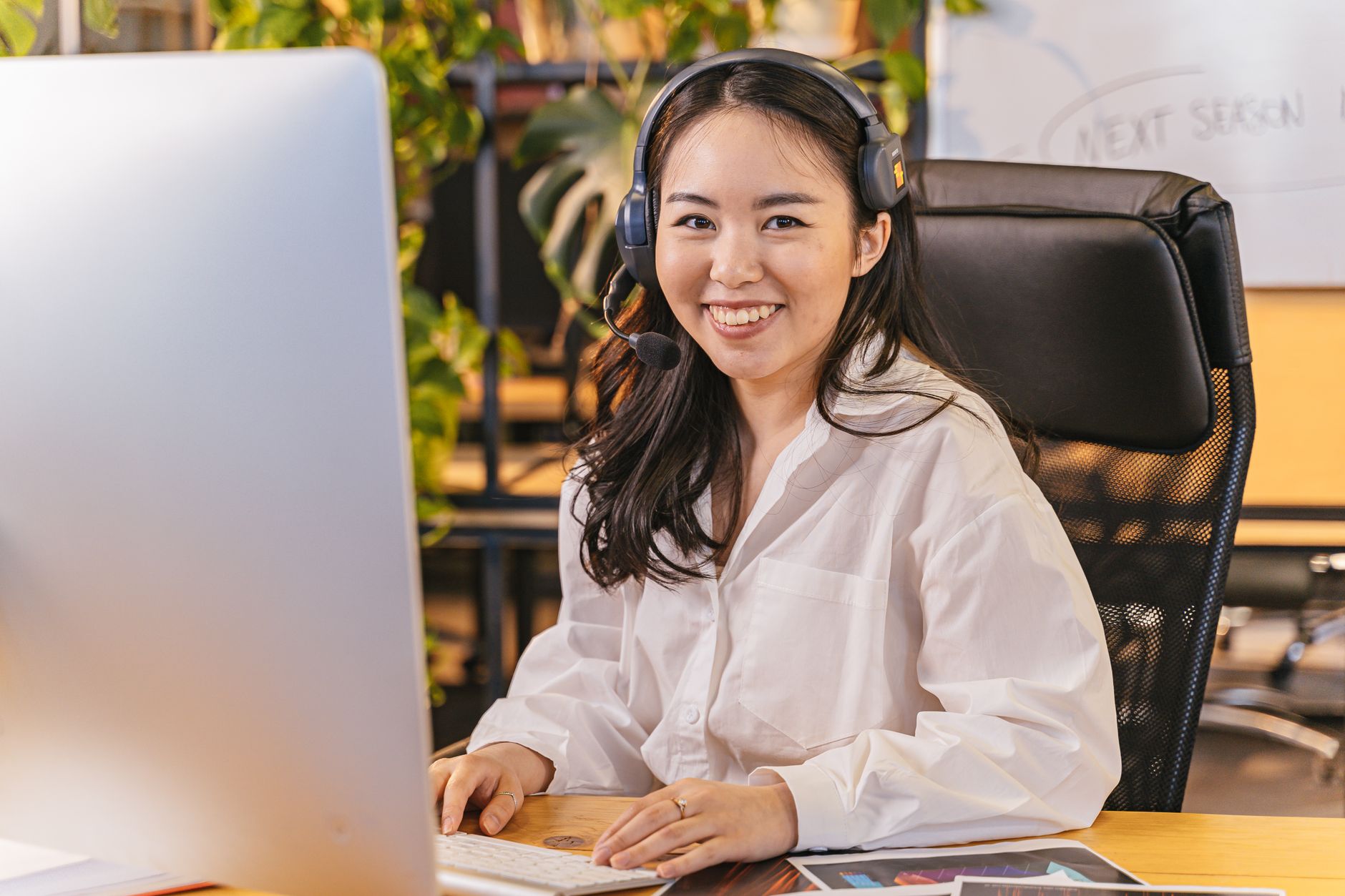 Smiling team member wearing a headset at her desk, ready to make a call