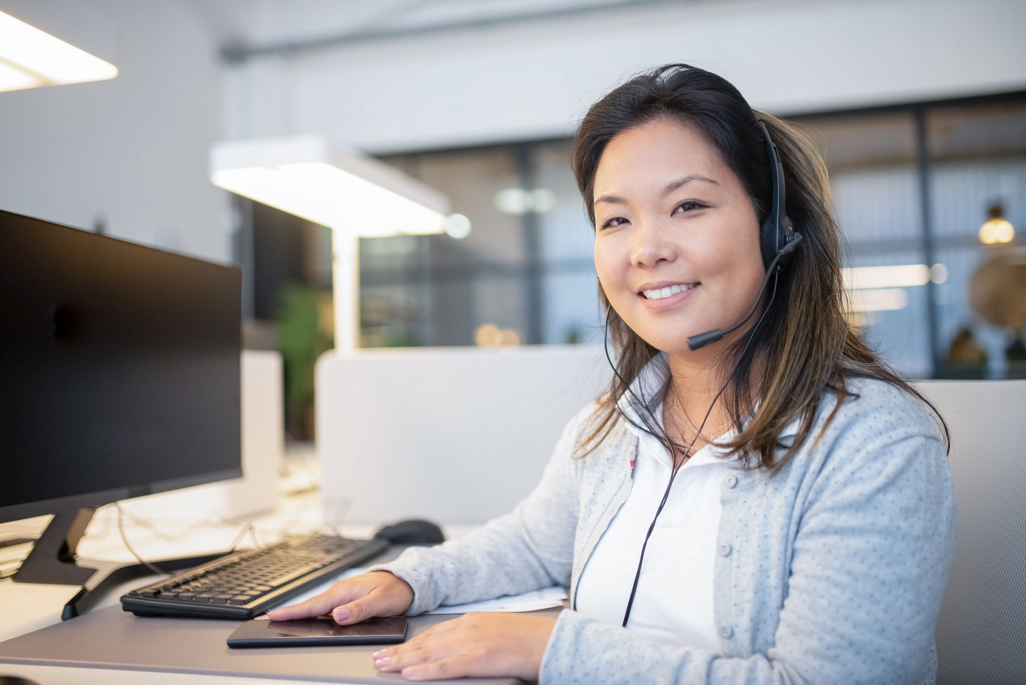 Smiling front-office team member wearing a headset at her desk