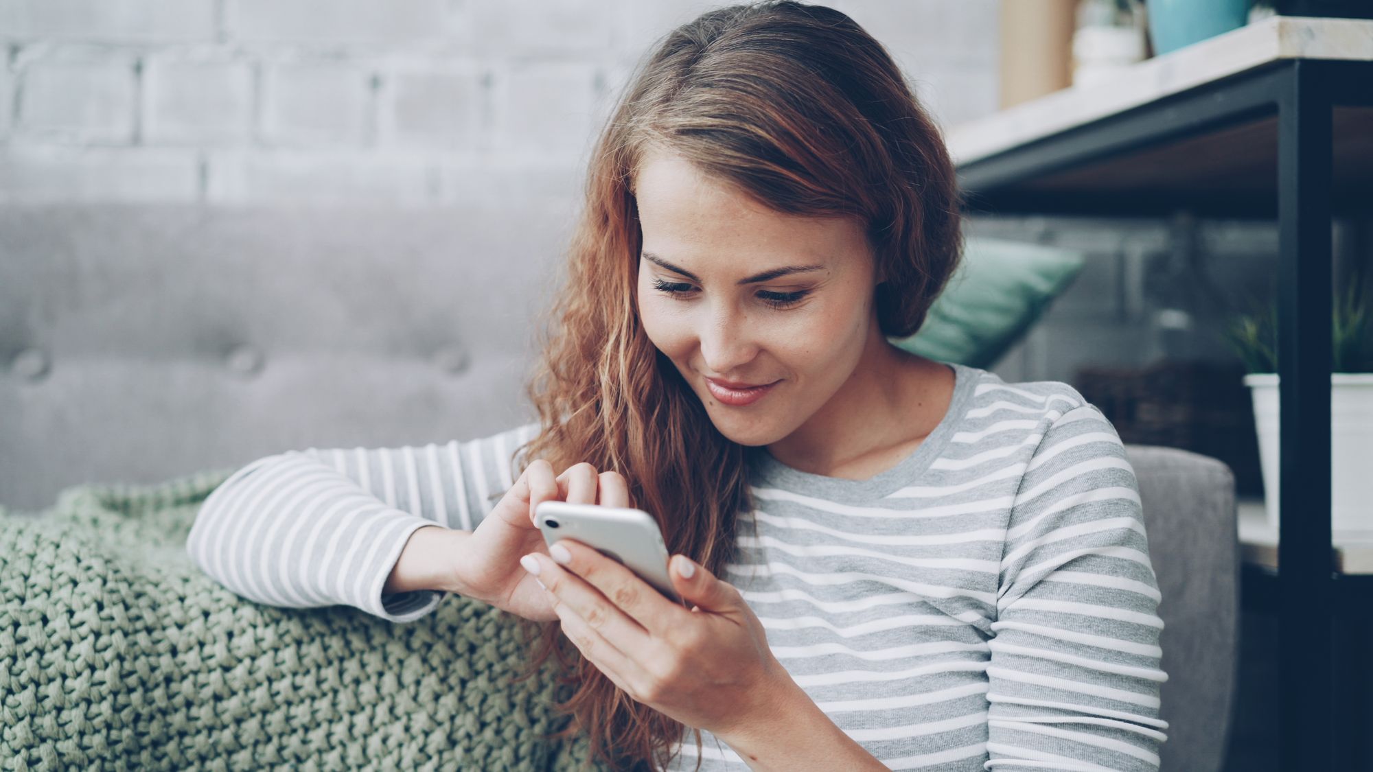 Woman at home filling in a form on her smartphone