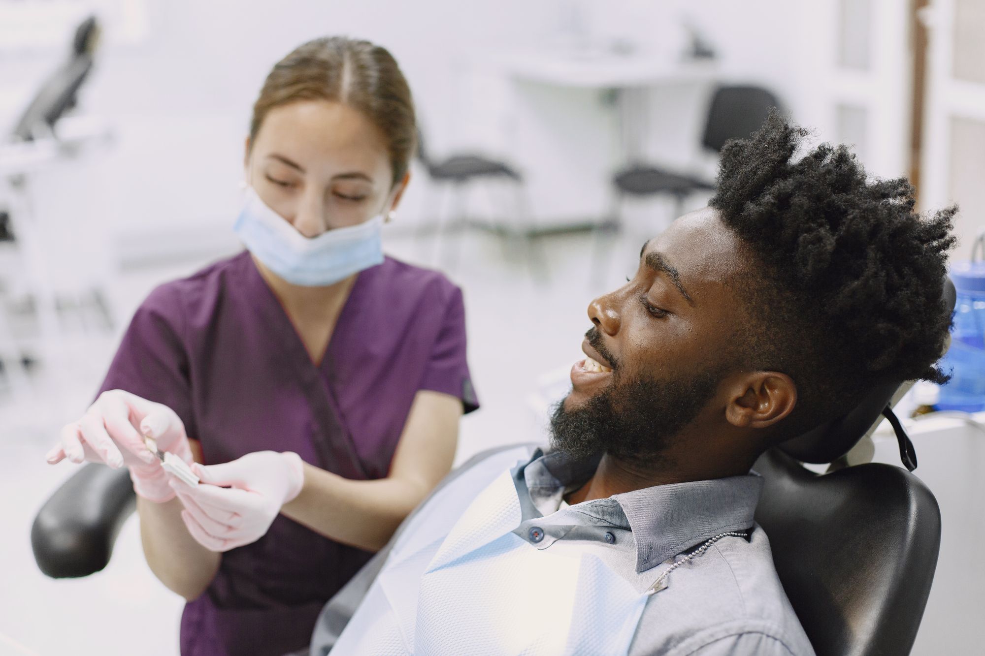 Patient smiling in the dental chair while a dental professional prepares for the exam