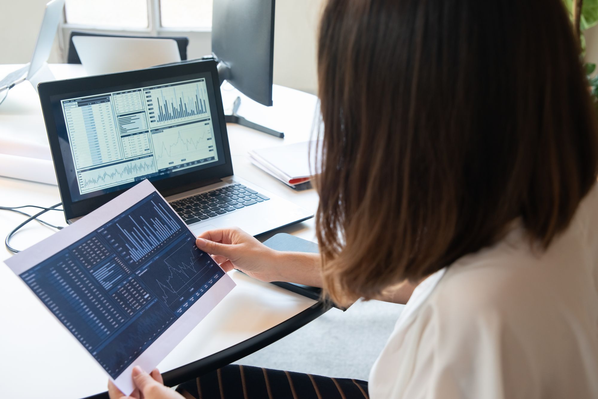Practice manager reviewing performance charts on a laptop and printout